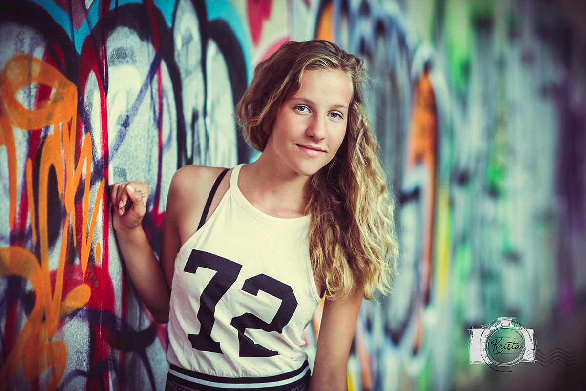 Dospívající dívka u graffiti zdi v tílku s číslem 72