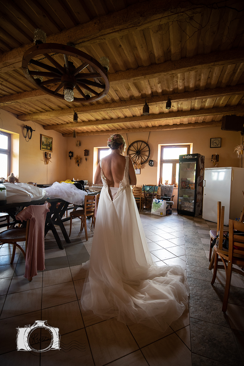 Nevěsta zezadu v šatech s dlouhou vlečkou